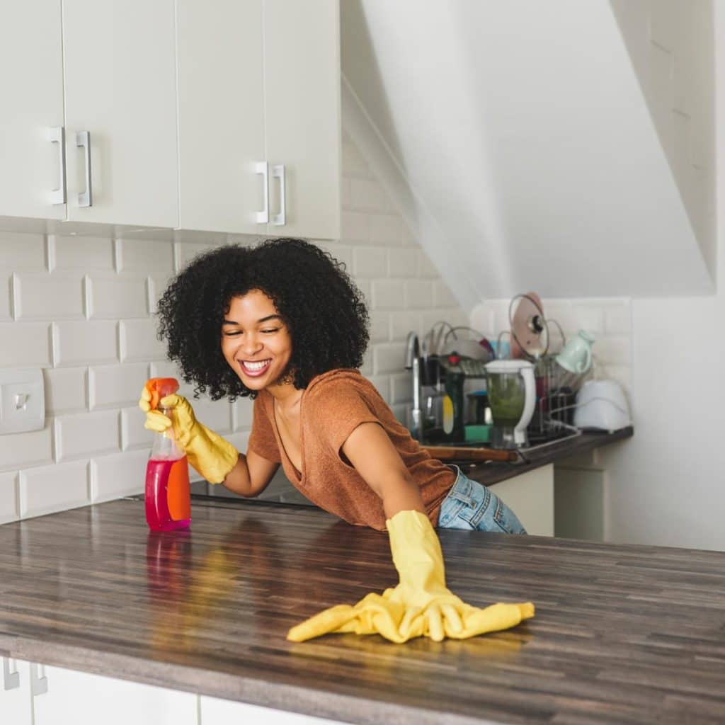 happy woman cleaning a kitchen counter